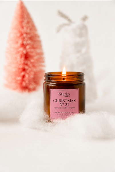 Lit Christmas No. 25 candle in festive snowy scene with pink tree